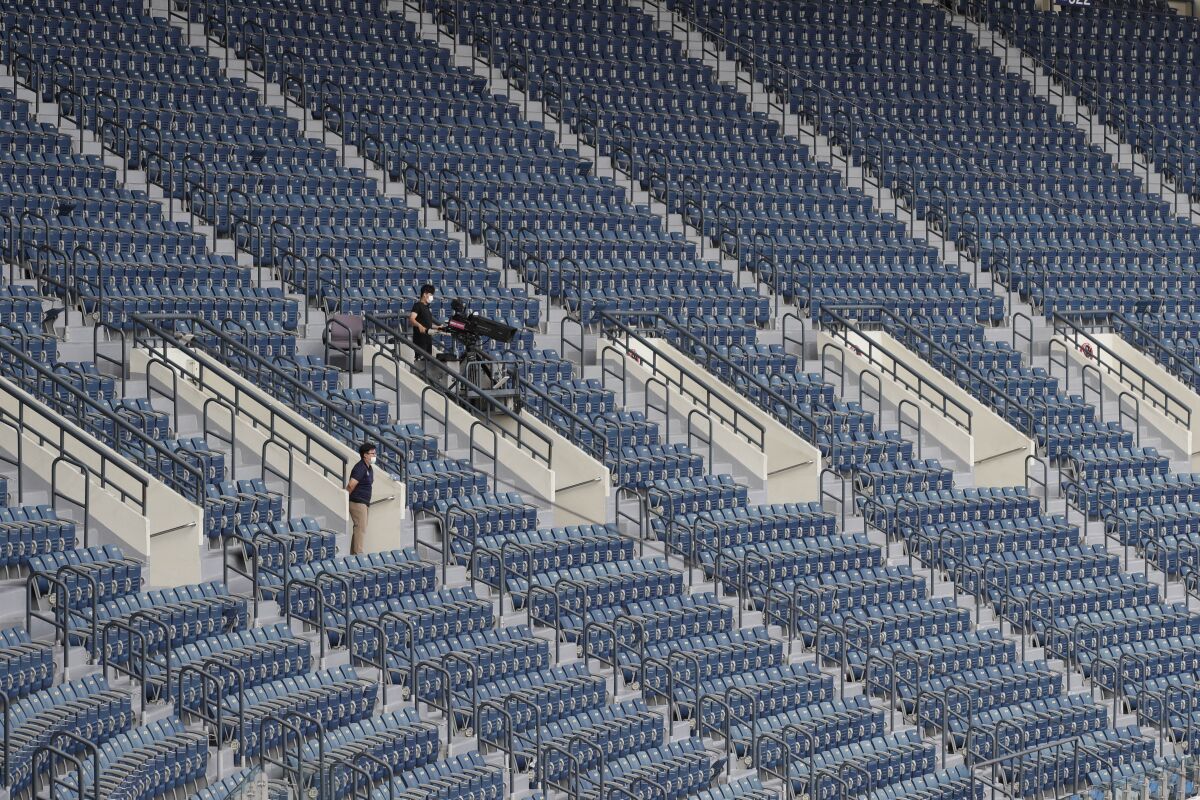 A TV cameraman works in rows of empty seats without fans as a precautionary measure during the KBO league baseball game between KT Wiz and Doosan Bears in Seoul, South Korea, Sunday, Aug. 16, 2020. Fans are banned once again from professional baseball and soccer games, which had just begun to slowly bring back spectators in late July. (AP Photo/Lee Jin-man)