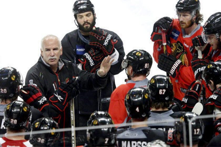 Chicago Blackhawks head coach Joel Quenneville, left, talks to his players at the end practice Tuesday before Game 1 of the Stanley Cup Final against the Boston Bruins on Wednesday.