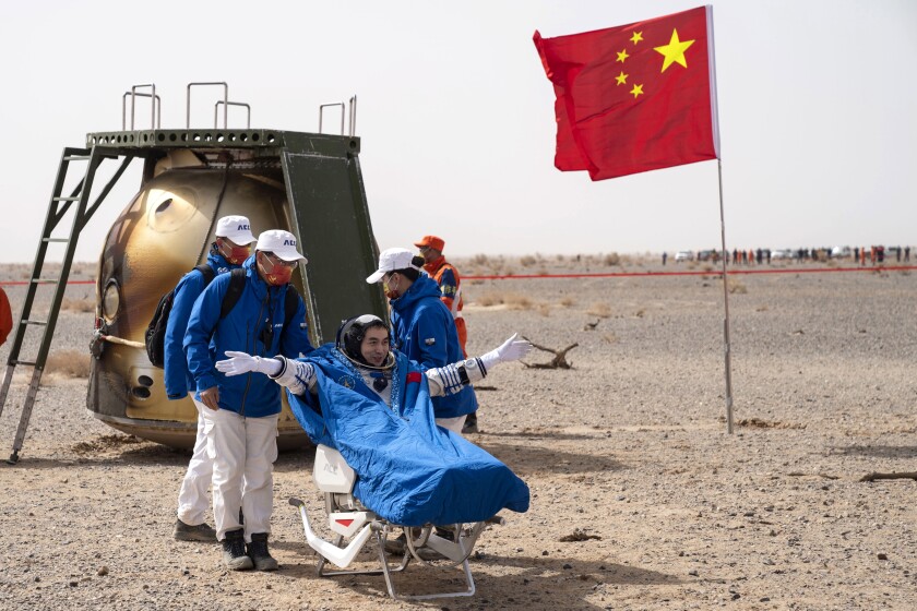 In this photo released by China's Xinhua News Agency, Chinese astronaut Ye Guangfu sits outside return capsule of the Shenzhou-13 manned space mission after landing at the Dongfeng landing site in northern China's Inner Mongolia Autonomous Region, Saturday, April 16, 2022. Three Chinese astronauts returned to Earth on Saturday after six months aboard China's newest space station in the longest crewed mission to date for its ambitious space program. (Cai Yang/Xinhua via AP)