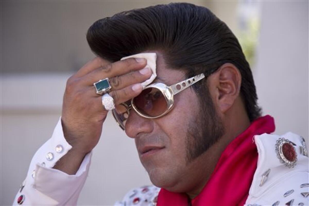 Las Vegas Elvis impersonator Cristian Morales wipes sweat from his brow in 112-degree heat on the Strip, where he was posing Thursday for photos with tourists.