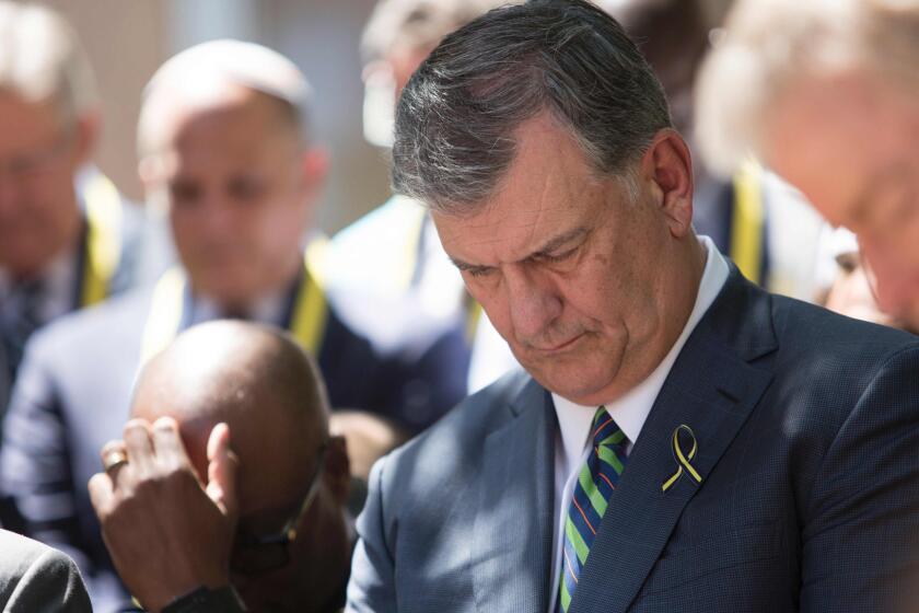 Dallas Mayor Mike Rawlings bows his head in prayer during an interfaith service Friday at Thanks-Giving Square.