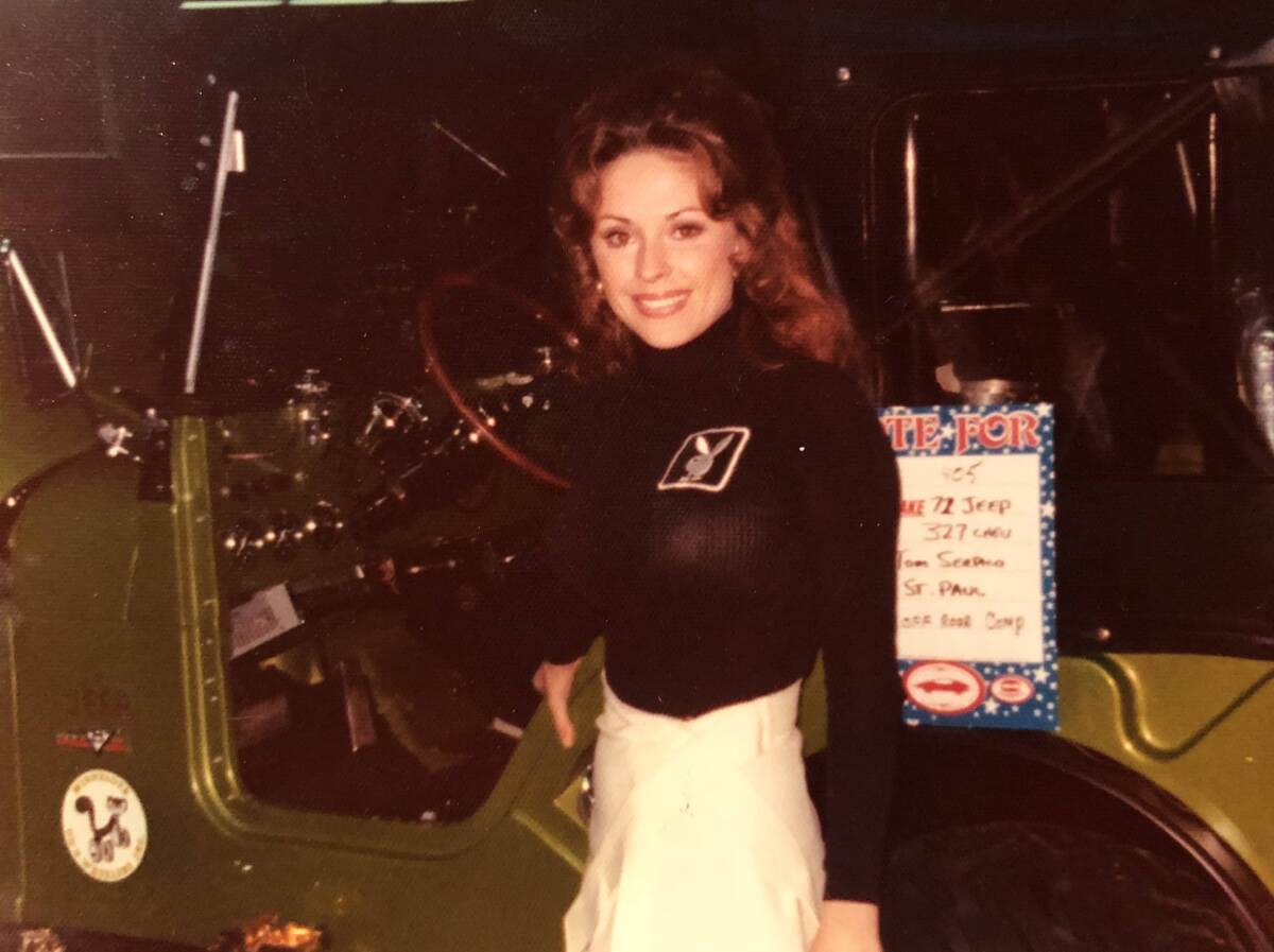 A woman poses by a Jeep wearing a sweater with a rabbit logo on it