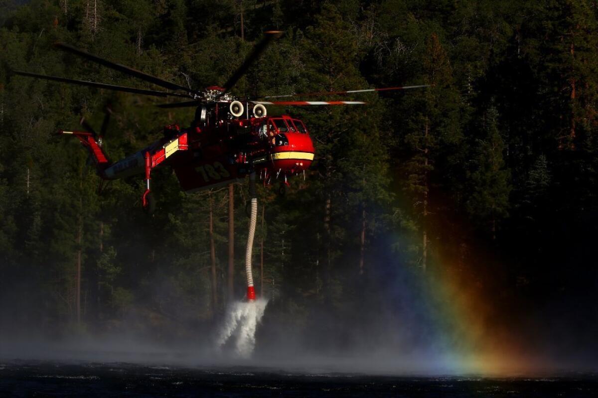 A helicopter scoops up water from Jenks Lake as it works to battle a wild fire that has burned more than 11,000 acres in the Big Bear area.