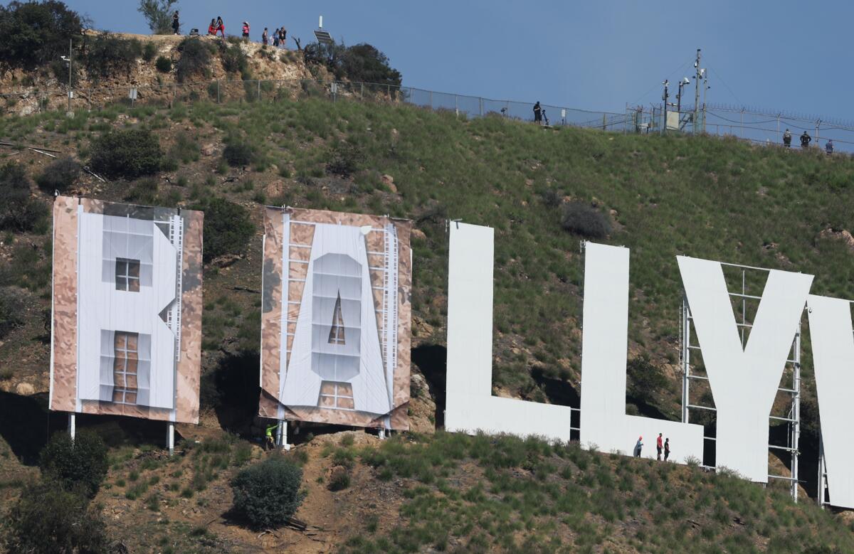 Workers install letters to cover the Hollywood sign