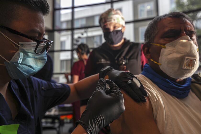 Pomona, CA - March 20: Chief medical officer Dr. Stephanie White, center, watches medical student Pierre Tran administers a coronavirus vaccine to a patient at Western University of Health Sciences on Saturday, March 20, 2021 in Pomona, CA.(Irfan Khan / Los Angeles Times)