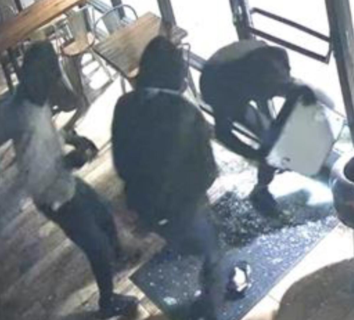 Surveillance video image of three people committing a burglary