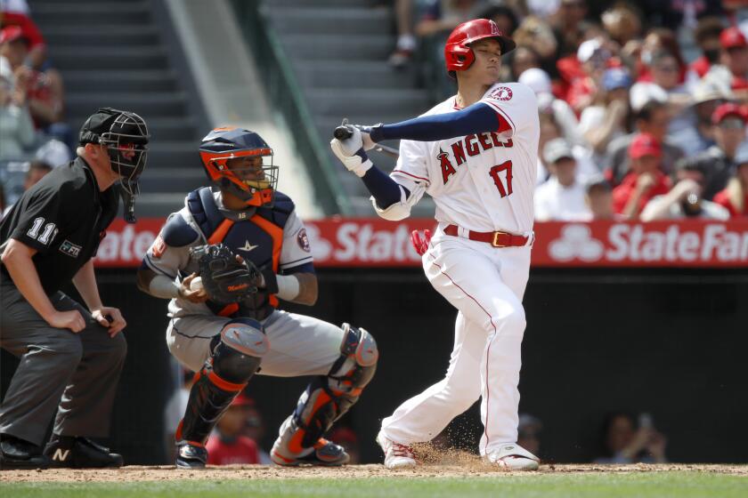 Los Angeles Angels' Shohei Ohtani, right, strikes out with Houston Astros catcher Martin Maldonado, center, and home plate umpire Tony Randazzo, left, looking on, during the sixth inning of a baseball game in Anaheim, Calif., Sunday, April 10, 2022. (AP Photo/Alex Gallardo)