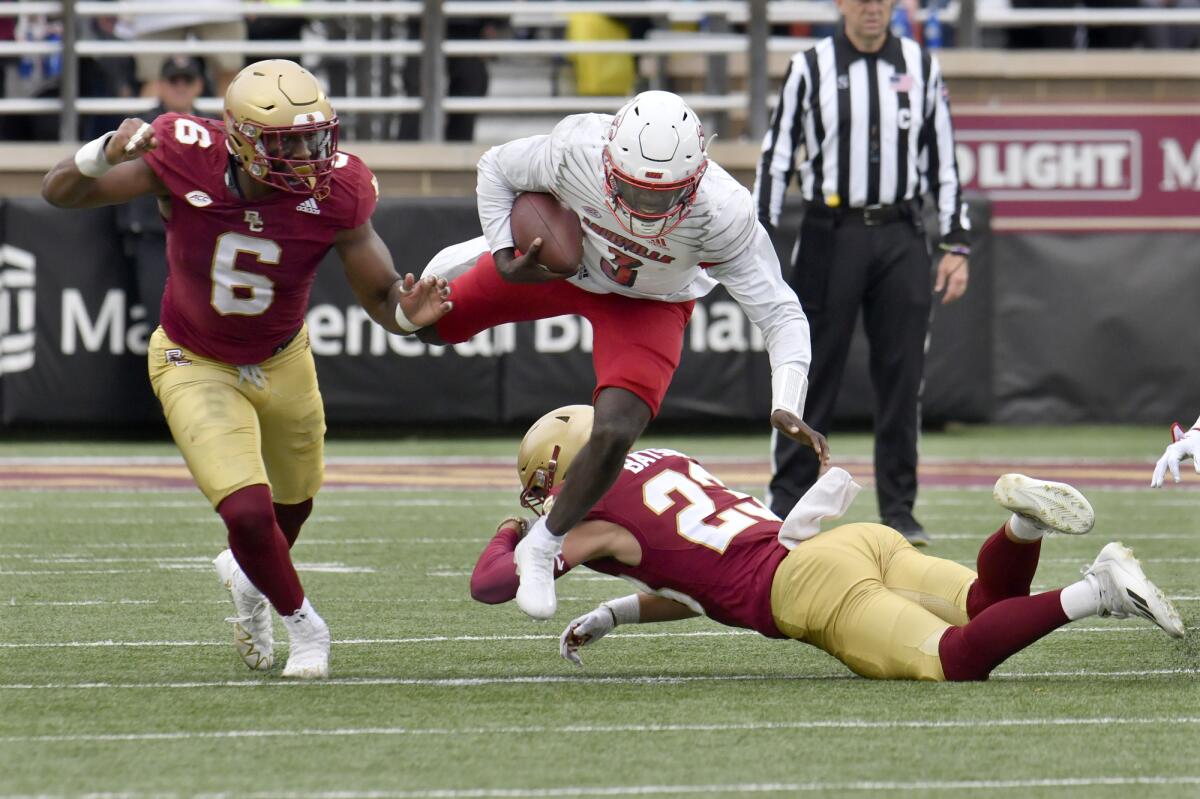 Louisville quarterback Malik Cunningham escapes the grasp of Boston College's Cole Batson during the fourth quarter of an NCAA college football game Saturday, Oct. 1, 2022, in Boston. At left is BC's Donovan Ezeiruaku (6). (AP Photo/Mark Stockwell)