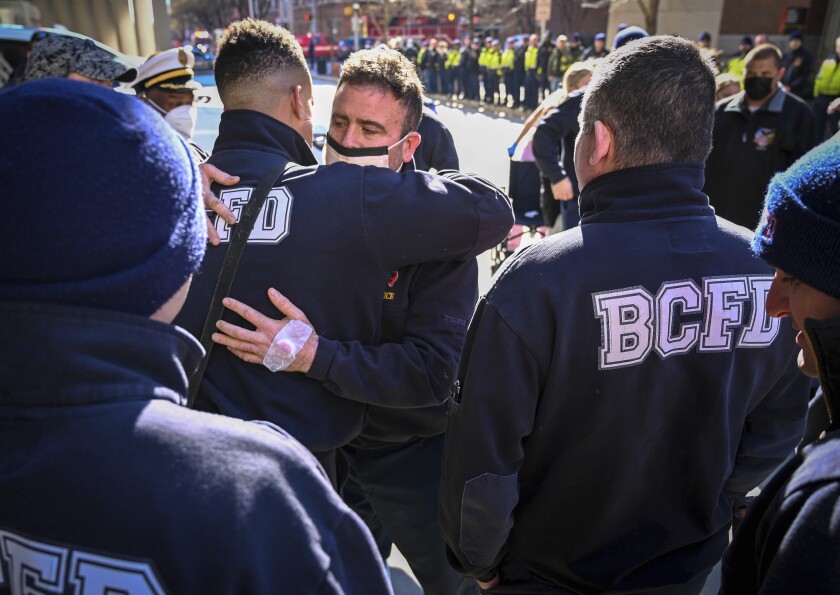 Baltimore firefighter John McMaster, center, who was injured in the fire and building collapse on Stricker Street Monday hugs fellow firefighters that were there to greet him as he was released from Shock Trauma Thursday, Jan. 27, 2022. (Jerry Jackson/The Baltimore Sun via AP)