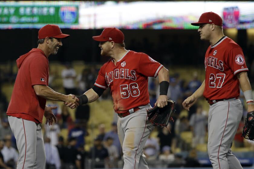 From left, Los Angeles Angels manager Brad Ausmus, right fielder Kole Calhoun (56) and center fielder Mike Trout (27) celebrate after a 5-4 win over the Los Angeles Dodgers during a baseball game Tuesday, July 23, 2019, in Los Angeles. (AP Photo/Marcio Jose Sanchez)