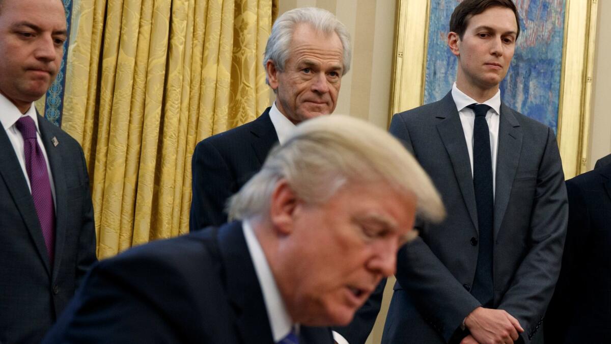 Trade advisor Peter Navarro stands between then-White House Chief of Staff Reince Priebus, left, and senior advisor Jared Kushner as President Trump signs an executive order in January.