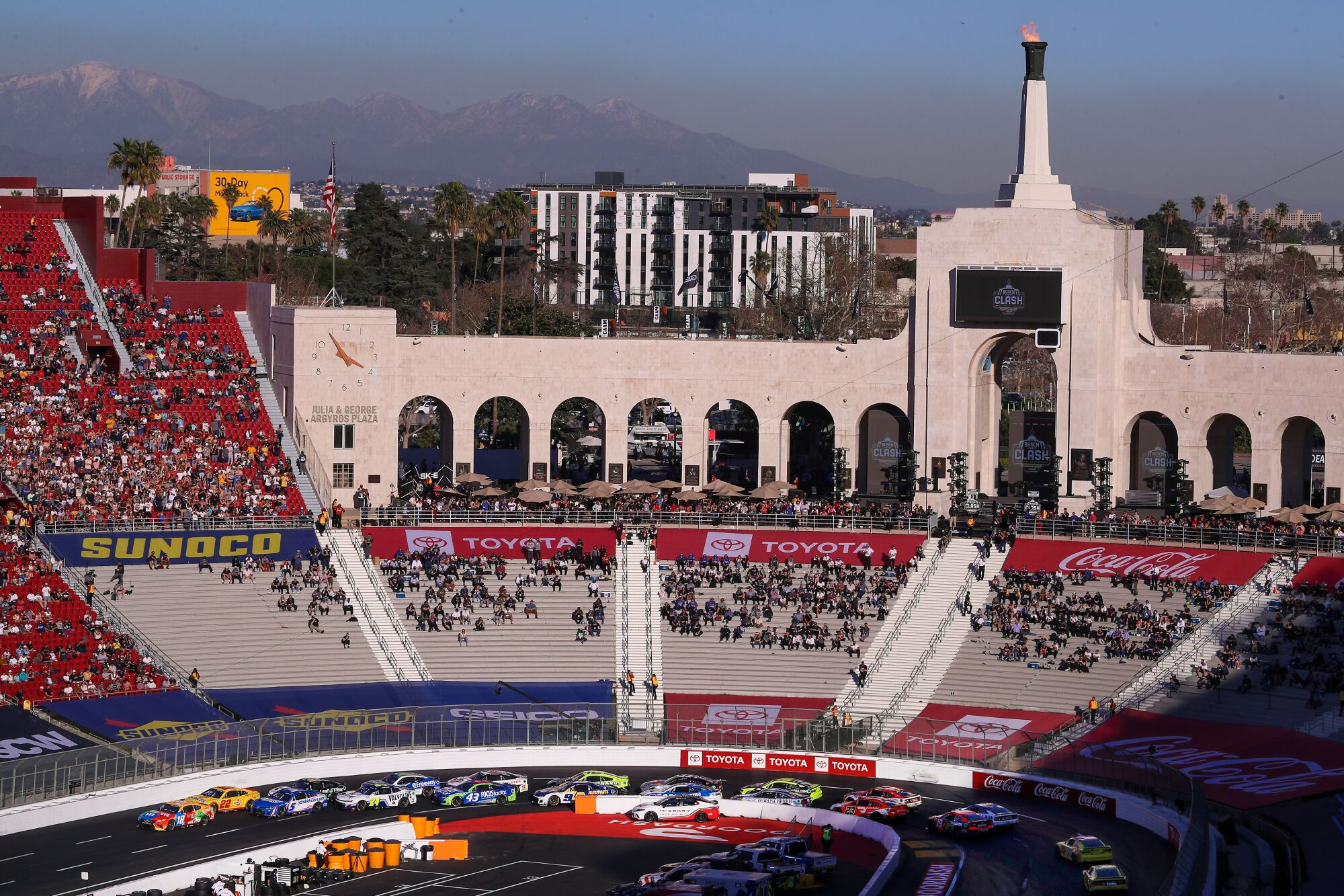 NASCAR racers circle with a view of the snow-capped mountains in the background.