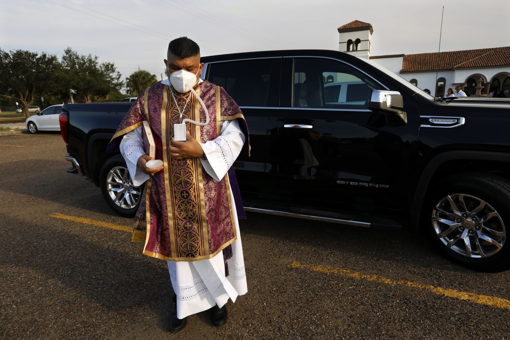 Deacon Joe Vargas wears an air purifier while conducting funerals in Brownsville, Texas.