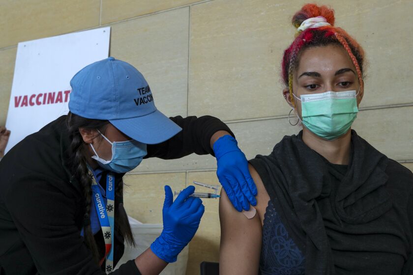 Los Angeles, CA - June 08: Thu Giang, a LVN, left, administers a Pfizer vaccine to Sibelle Yuksek, at newly inaugurated vaccine site at Union Station on Tuesday, June 8, 2021 in Los Angeles, CA. (Irfan Khan / Los Angeles Times)