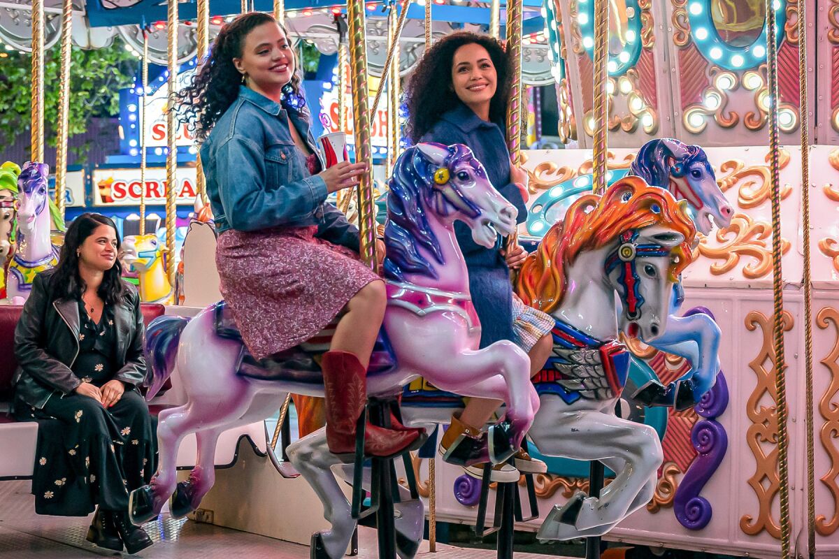 Three women ride on a carousel 