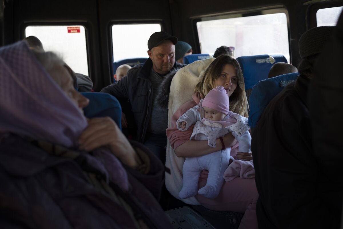 Anastasia Vizavik holds one of her six children inside a bus at the city of Bashtanka, Mykolaiv district, Ukraine, on Thursday, April 7, 2022. Vizavik and her family are fleeing the town of Chernobaievka in Kherson province, which is occupied by the Russian forces. (AP Photo/Petros Giannakouris)