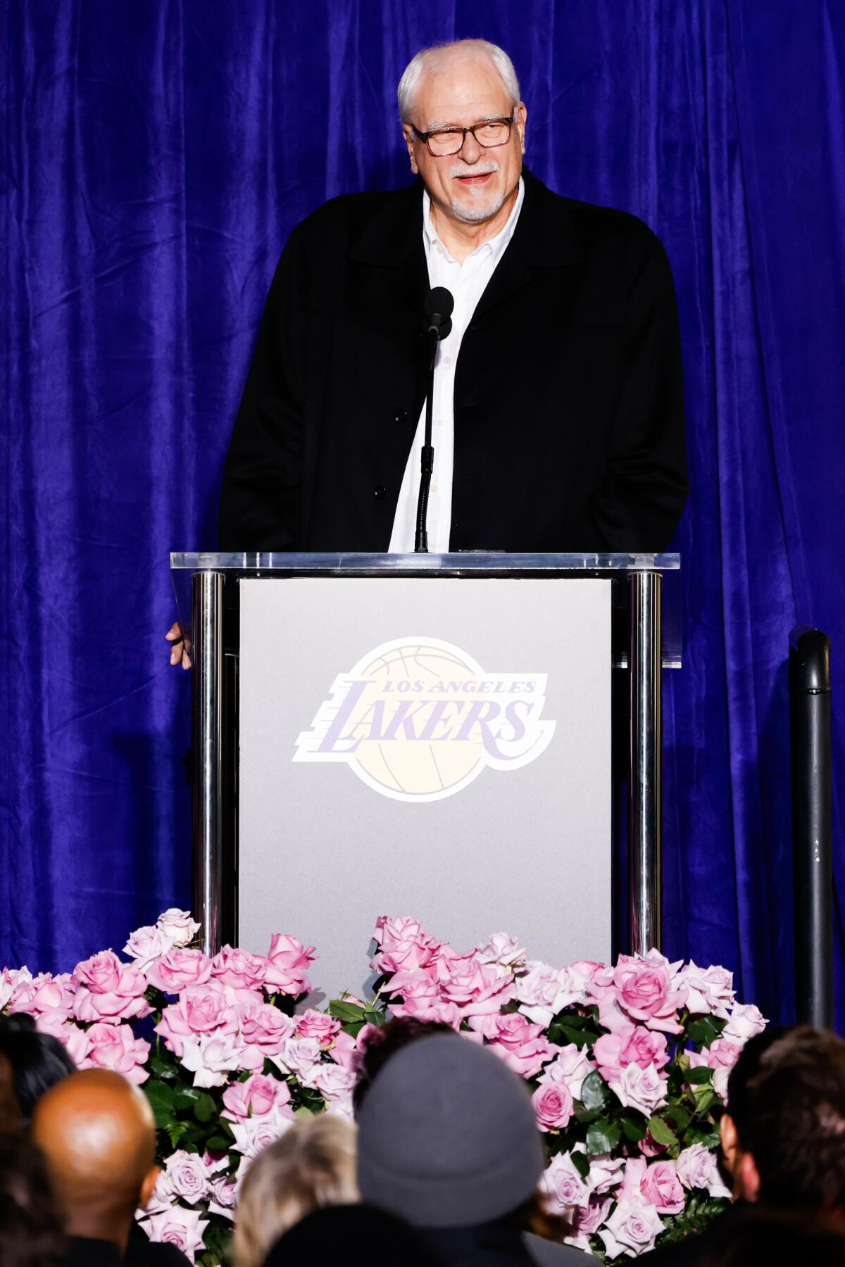 Phil Jackson stands at a podium and speaks as the Los Angeles Lakers unveil a statue honoring the late Kobe Bryant.