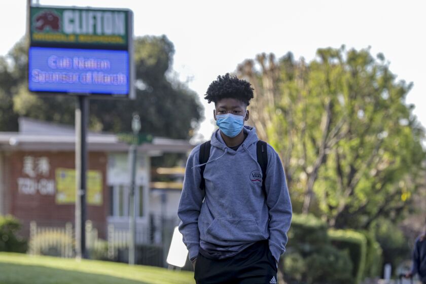 MONROVIA, CA - MARCH 04, 2020 - Joshua Guyton, in face mask as a precautionary measure, arrives at Clifton Middle School in Monrovia that was open Thursday March 05, 2020 after crews performed a deep cleaning overnight after a parent came in contact with someone exposed to the novel coronavirus. The parent has a student who attends Clifton Middle School, but the Monrovia Unified School District said in a statement neither the parent or their children have shown signs of any coronavirus symptoms, but placed themselves in self-isolation for 14 days. (Irfan Khan / Los Angeles Times)