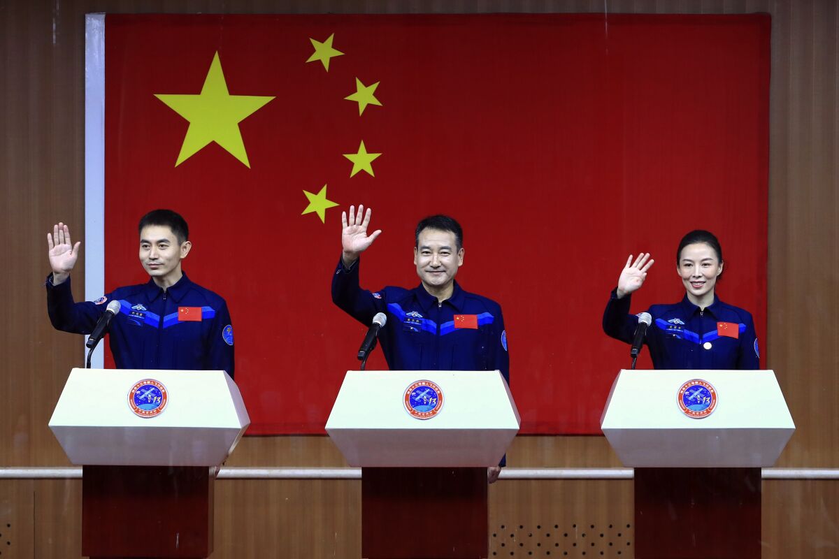 In this photo released by Xinhua News Agency, Chinese astronauts, from left, Ye Guangfu, Zhai Zhigang and Wang Yaping wave to reporters as they arrive for a press conference at the Jiuquan Satellite Launch Center ahead of the Shenzhou-13 launch mission from Jiuquan in northwestern China, Thursday, Oct. 14, 2021. China is preparing to send three astronauts to live on its space station for six months — a new milestone for a program that has advanced rapidly in recent years. (Ju Zhenhua/Xinhua via AP)