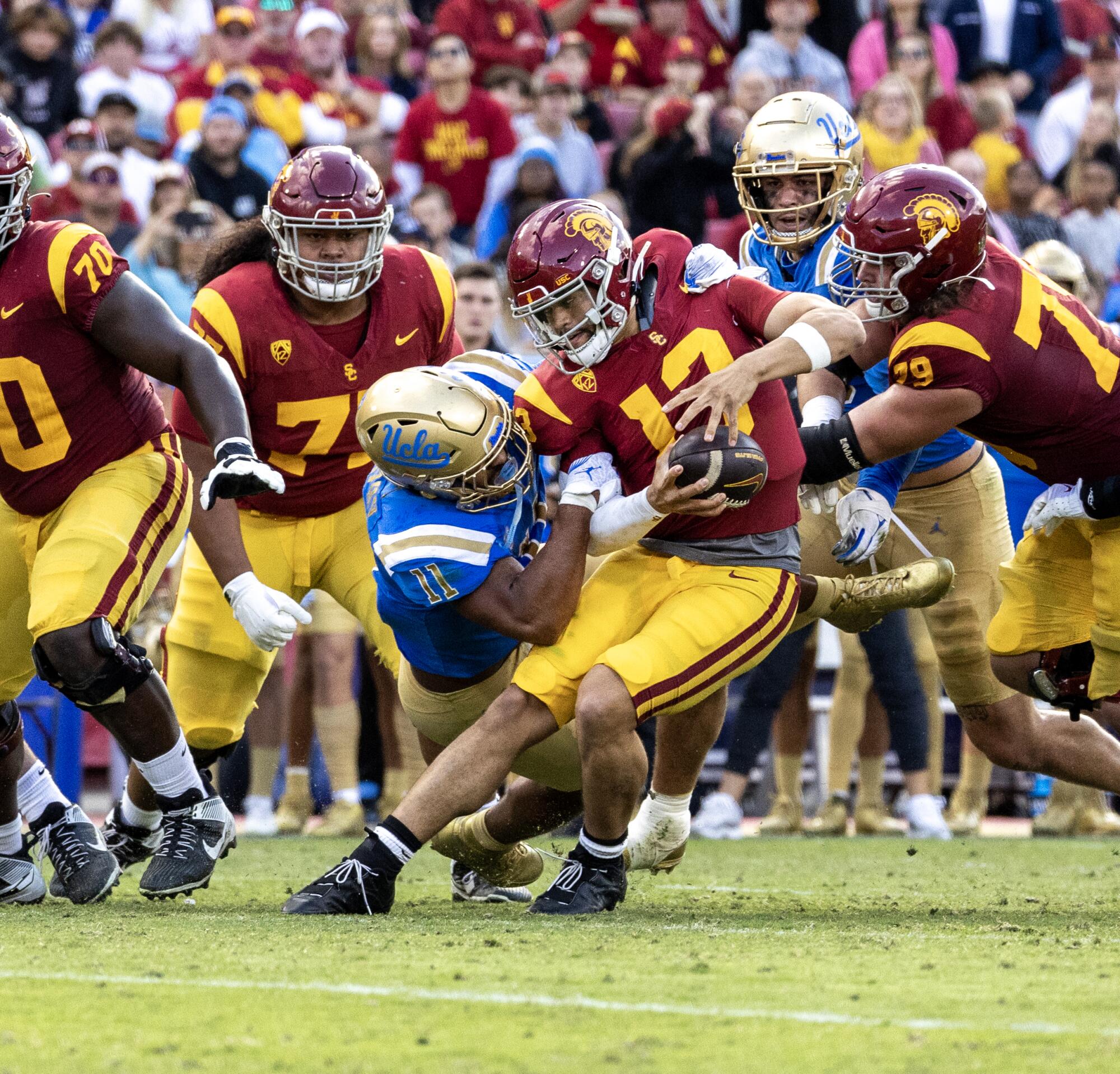 USC quarterback Caleb Williams gets sacked by UCLA's Gabriel Murphy as his teammates look on
