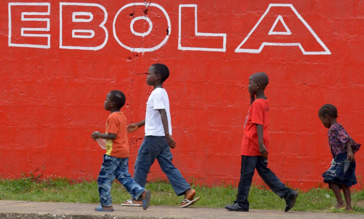 Children walk past an Ebola slogan painted on a wall in the Liberian capital, Monrovia, in August 2014.