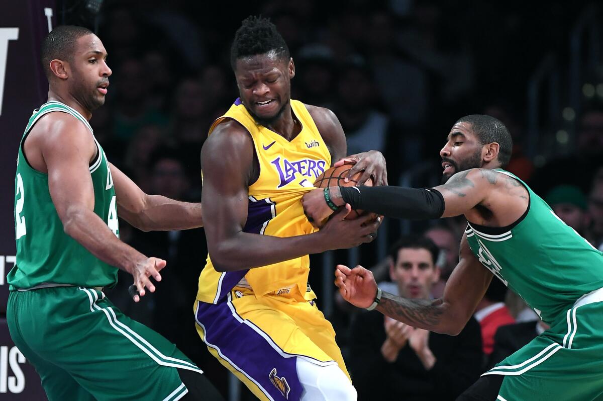 Lakers forward Julius Randle tries to power his way through the double-team defense of Celtics Kyrie Irving, right, and Al Horford during a game last season.
