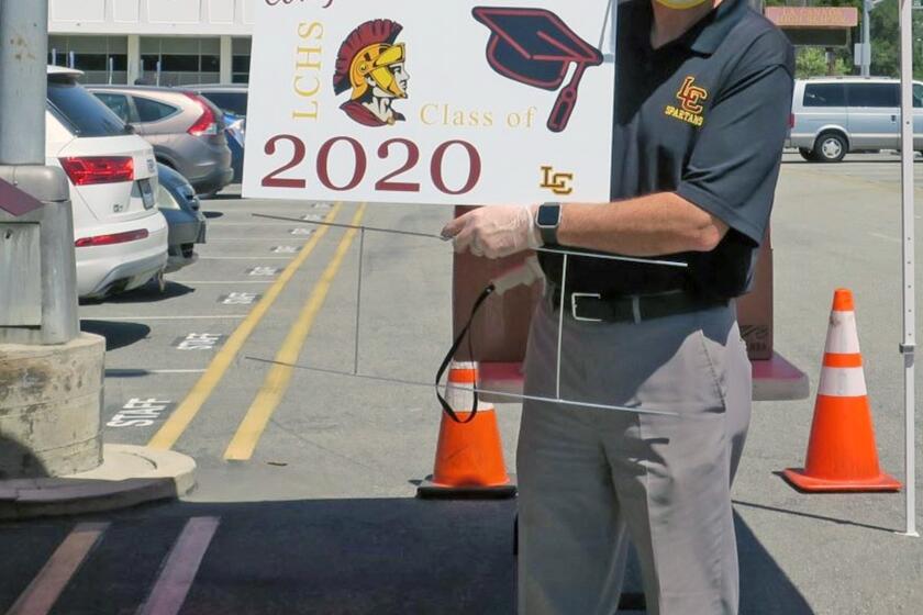 La Canada High School Principal Jim Cartnal holds a sign being given to all LCHS seniors to display in their yards and photograph, part of a series of stand-in celebrations for traditional senior year activities canceled during the coronavirus pandemic. (Photo by Sara Cardine)