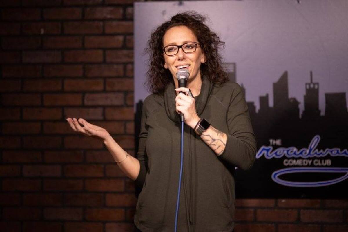 A female comedian holds a microphone to her mouth.