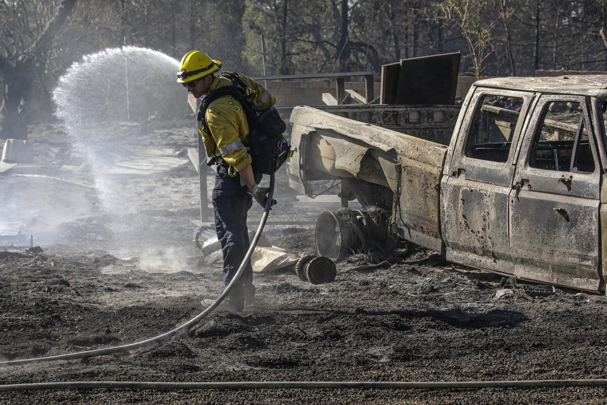 San Bernardino County firefighter Mathew Safdeye douses hot spots from the South fire in Lower Lytle Creek.