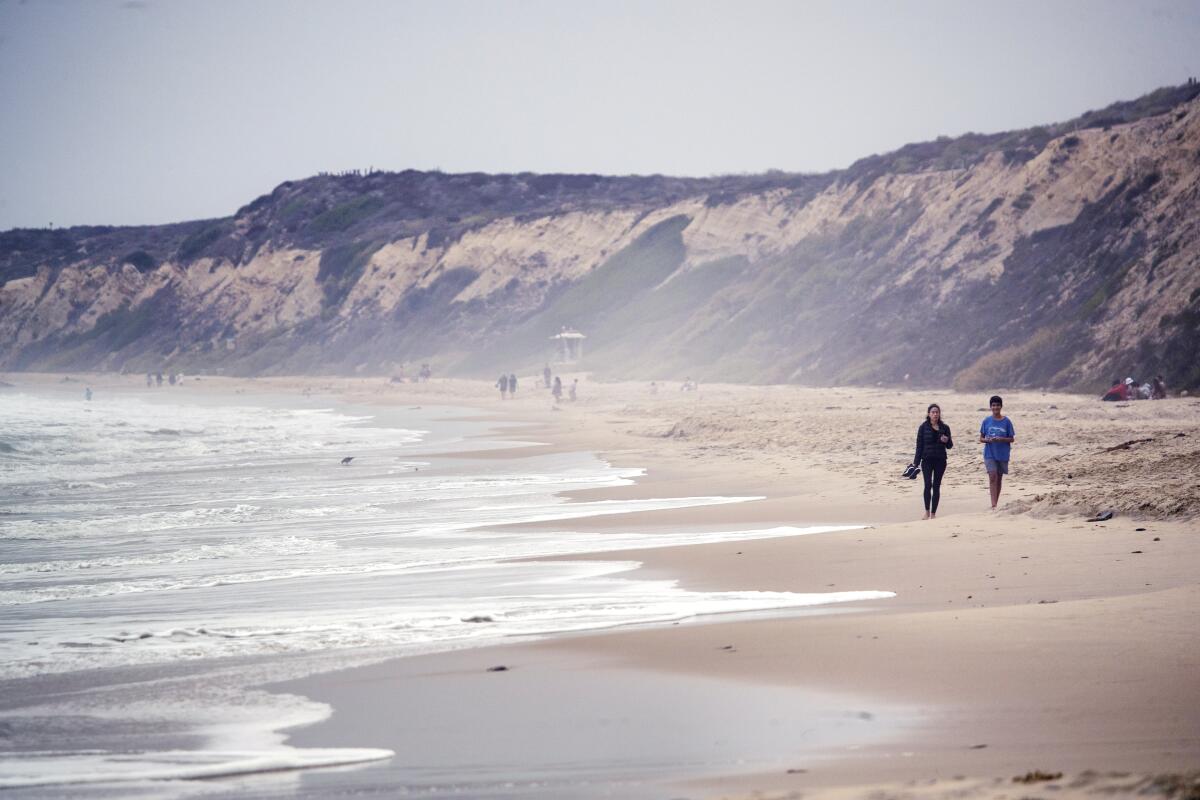 Beachcombers walk along Crystal Cove State Beach.