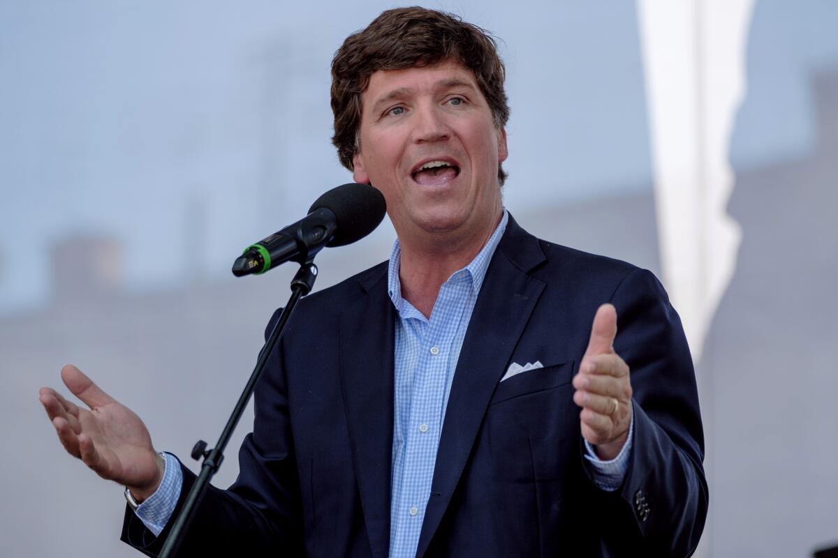 Tucker Carlson talking into a microphone on a stand