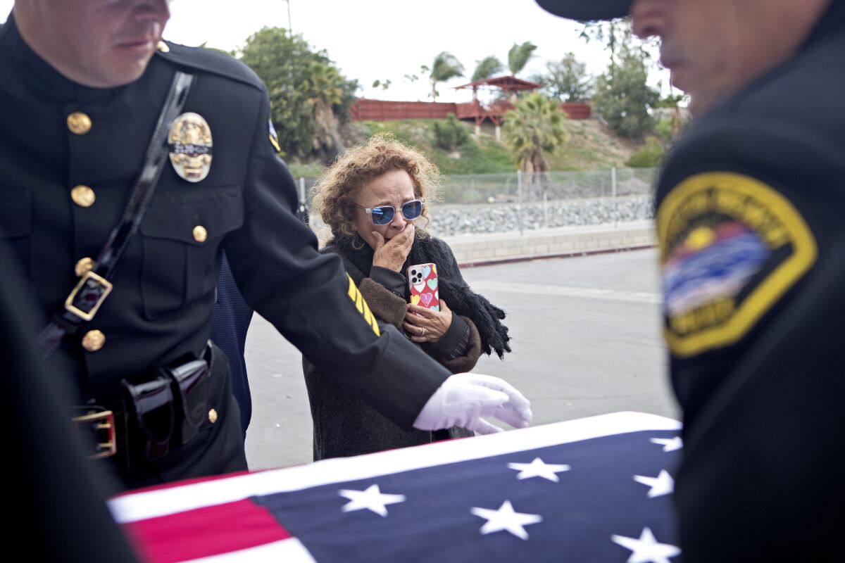 A woman cries next to a casket covered in a U.S. flag