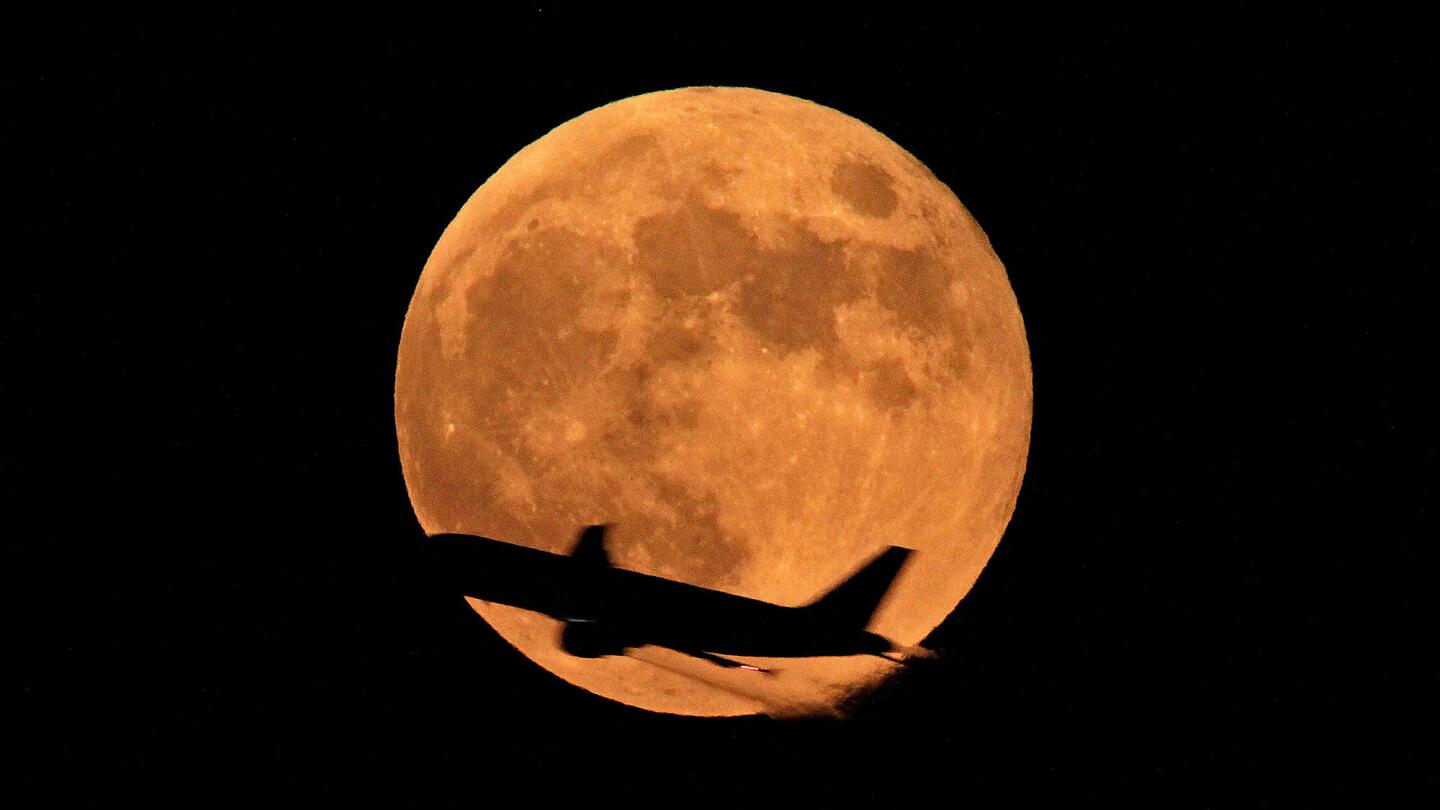 An airliner crosses the full moon in Lahore, Pakistan, on Oct. 8 as the moon casts an orange glow.
