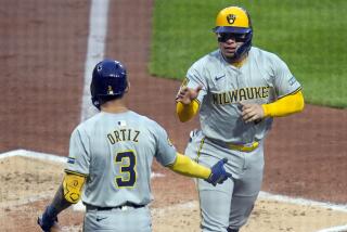 El venezolano William Contreras, de los Cerveceros de Milwaukee, es felicitado por Joey Ortiz, tras anotar en el juego del miércoles 24 de abril de 2024, ante los Piratas de Pittsburgh (AP Foto/Gene J. Puskar)