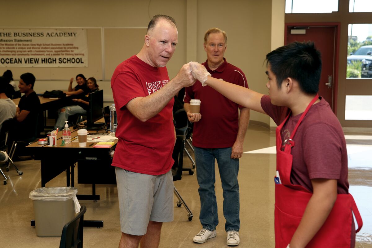 Ocean View teacher John Volo, center, shares a fist pound with IDEAs student Hong Lai, 16, right, after he delivered coffee.