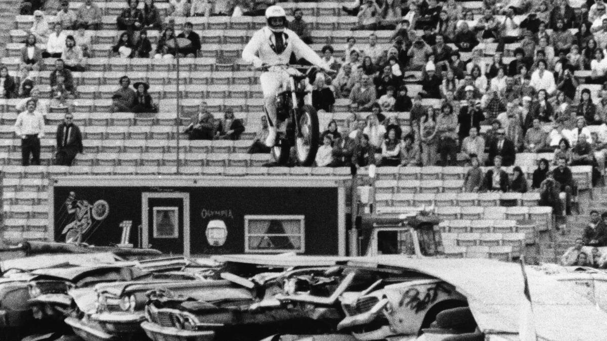 Evel Knievel leaps the smashed bodies of more than 50 cars, set 18 abreast, on his motorcycle in a stunt at the Coliseum on Feb. 18, 1973.