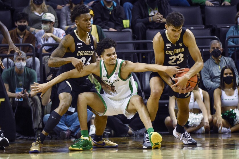 Colorado forward Tristan da Silva (23) steals the ball from Oregon guard Will Richardson (0) as Colorado guard Elijah Parquet (24) helps on the play during the second half of an NCAA college basketball game Tuesday, Jan. 25, 2022, in Eugene, Ore. (AP Photo/Andy Nelson)