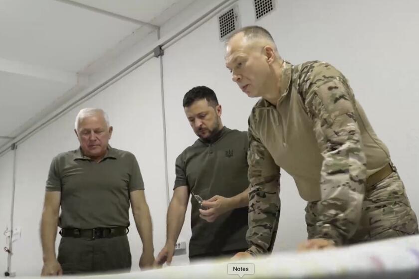 In this photo provided by the Ukrainian Presidential Press Office, Ukrainian President Volodymyr Zelenskyy, center, Commander-in-Chief Oleksandr Syrsky, right, look at a map during their visit to Sumy, Ukraine, Thursday, Aug. 22, 2024. (Ukrainian Presidential Press Office via AP)