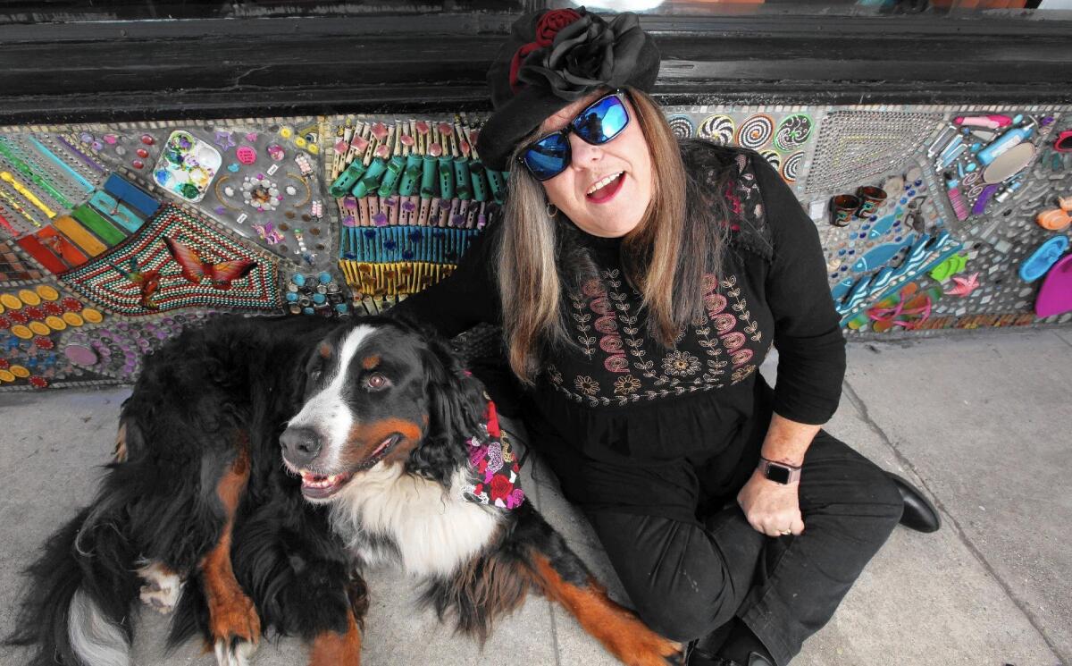 Renee Howard, pictured with her dog Dudley, has created a mosaic at Color Lounge, a Burbank hair salon, using everyday items, including press-on fingernails, hair-trimmer guides and old computer components.