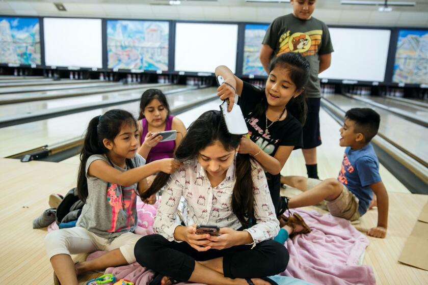 PORT ARTHUR, TEXAS -- THURSDAY, AUGUST 31, 2017: Fatima Flores, 12, center, gets her hair done by Shelly Flores, 7, left, and Ashley Flores, 7, as their family take shelter at Max Bowl, a local bowling alley after they were evacuated from their homes in Groves due to rising floodwater caused by Tropical Storm Harvey in Port Arthur, Texas, on Aug. 31, 2017. (Marcus Yam / Los Angeles Times)