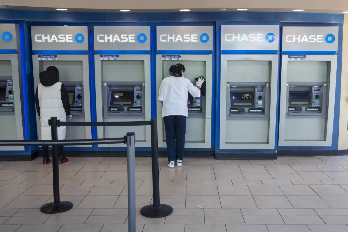 ARCHIVO -  una empleada del banco Chase desinfecta cajeros automáticos en una sucursal de Queens, Nueva York. 