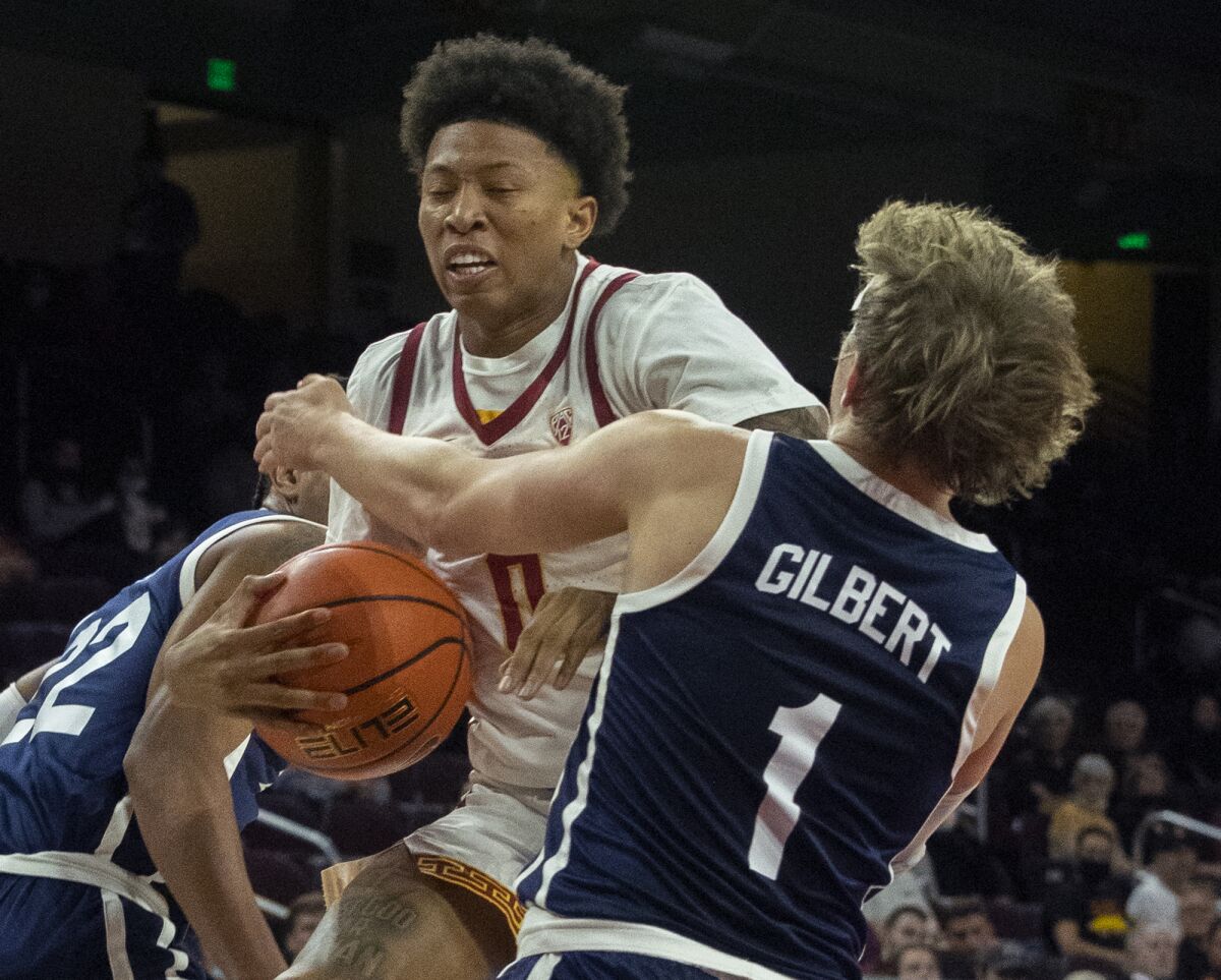 USC guard Boogie Ellis is tied up under the rim by Dixie State's Brock Gilbert.