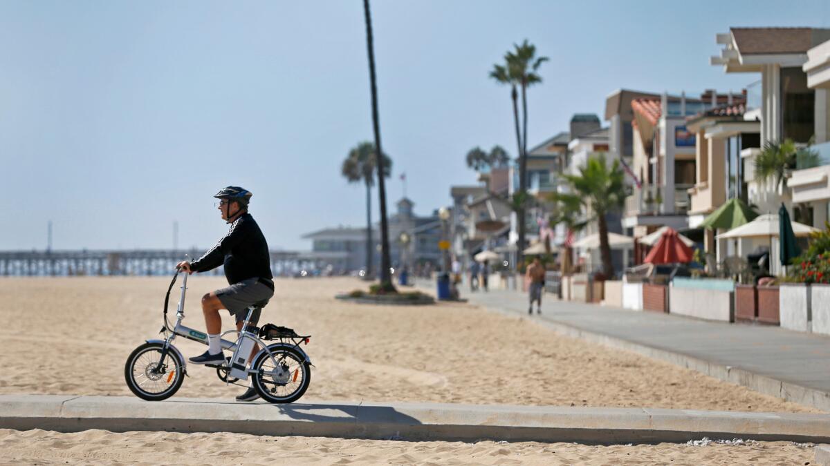 Ken Montgomery of Irvine shows off his e-bike just off the sand in Newport Beach.