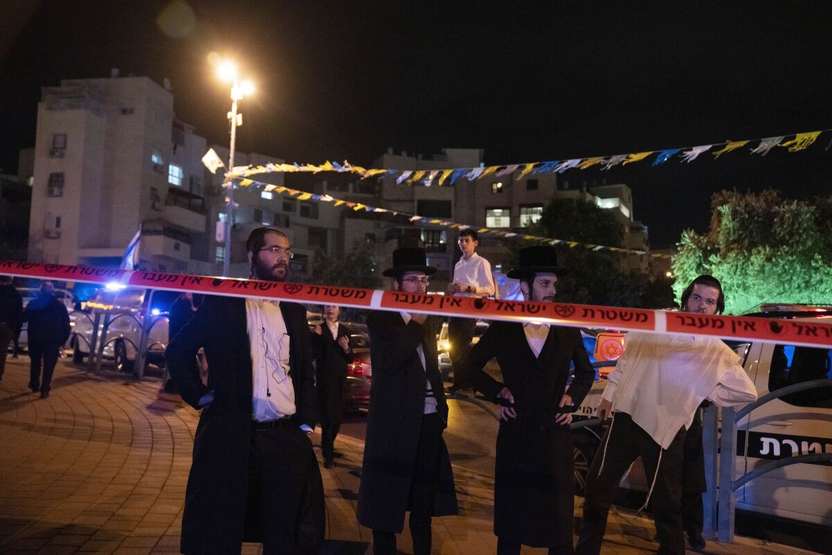 Ultra-Orthodox Jews standing behind police tape after an attack in Israel