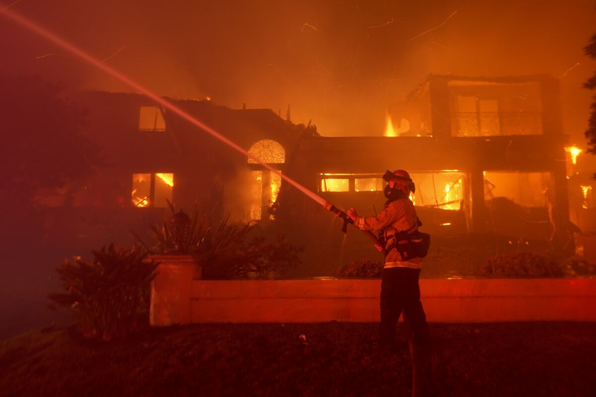 A firefighter works to put out a structure burning during a wildfire Wednesday, May 11, 2022, in Laguna Niguel, Calif. (AP Photo/Marcio J. Sanchez)