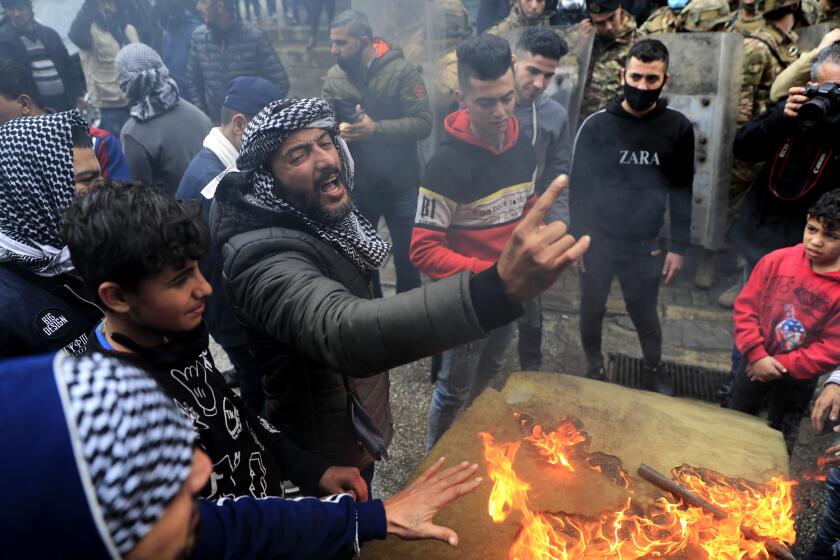 A protester shouts slogans in front the house of a Lebanese lawmaker, during a protest against deteriorating living conditions and strict coronavirus lockdown measures, in Tripoli, north Lebanon, Thursday, Jan. 28, 2021. Violent confrontations overnight between protesters and security forces in northern Lebanon left a 30-year-old man dead and more than 220 people injured, the state news agency said Thursday. (AP Photo/Hussein Malla)