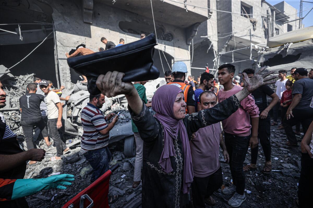 A woman with dirt on her hands gestures as people work to find victims in buildings hit by airstrikes in the Gaza Strip.