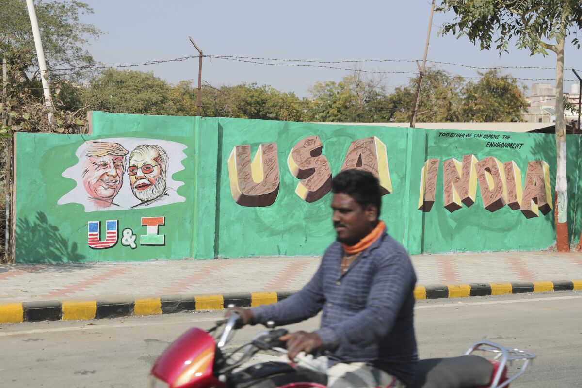 A man rides past a wall painted with portraits of U.S. President Trump and Indian Prime Minister Narendra Modi in Ahmadabad, India, on Tuesday. Trump is scheduled to visit the city next week.