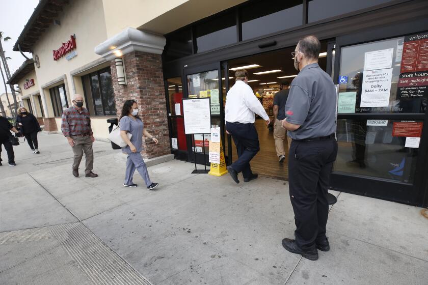 TORRANCE, CA - APRIL 27: Vons store supervisor Anthony Capone, right, greets shoppers as they are allowed in at 7 a.m. to the Vons located at 24325 Crenshaw Blvd in Torrance. Doors opened at 6 a.m. for seniors and at-risk shoppers due to the Coronavirus. Most of the team arrives at 5 a.m. to stock the shelves with product, sanitize the location for staff and shoppers, and picker/shoppers begin to collect items for .com home delivery shoppers. Vendors arriving throughout the morning must read a checklist of warnings, sign in and they must wear face covering. Vons on Monday, April 27, 2020 in Torrance, CA. (Al Seib / Los Angeles Times)