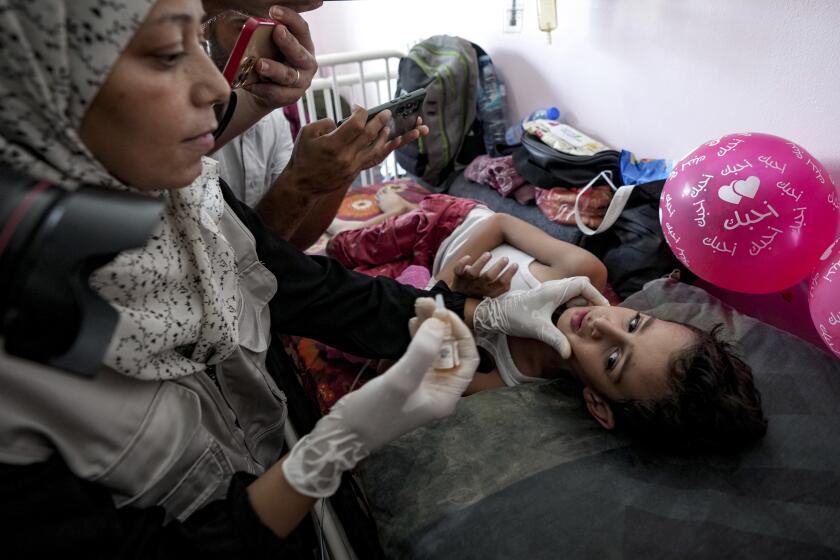 A health worker administers a polio vaccine to a child at a hospital in Khan Younis, Saturday, Aug. 31, 2024. (AP Photo/Abdel Kareem Hana)